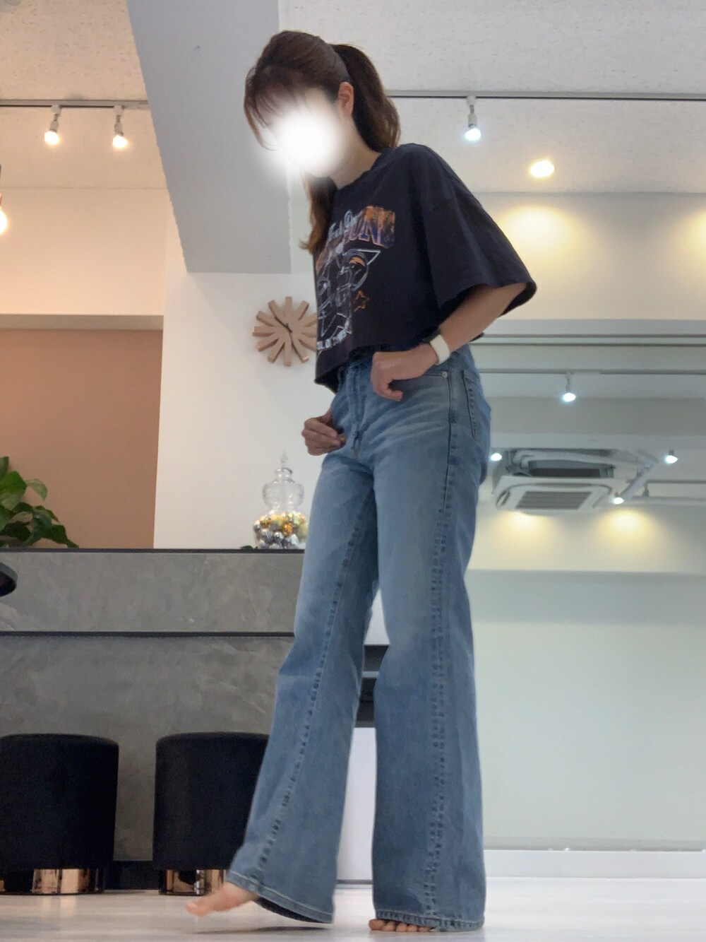 ブルー系のデニムパンツ、ブラック系のサンダル、ブラック系のTシャツ/カットソーを着用したレディースの夏コーディネートの2枚目の写真