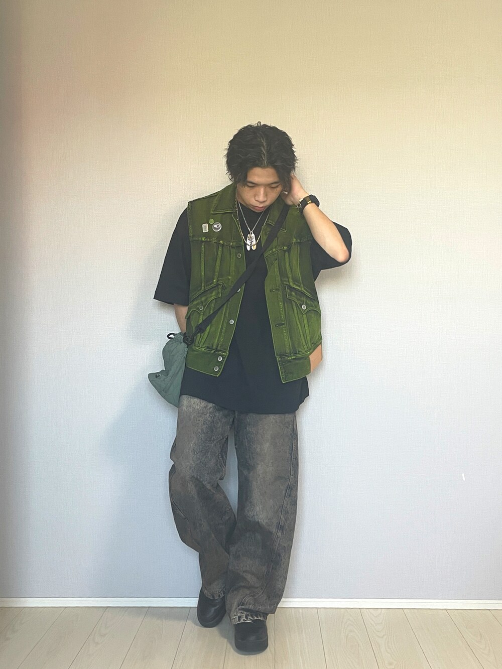 ブラック系のスニーカー、ブルー系のデニムパンツ、イエロー系のベストを着用したメンズの秋コーディネートの2枚目の写真