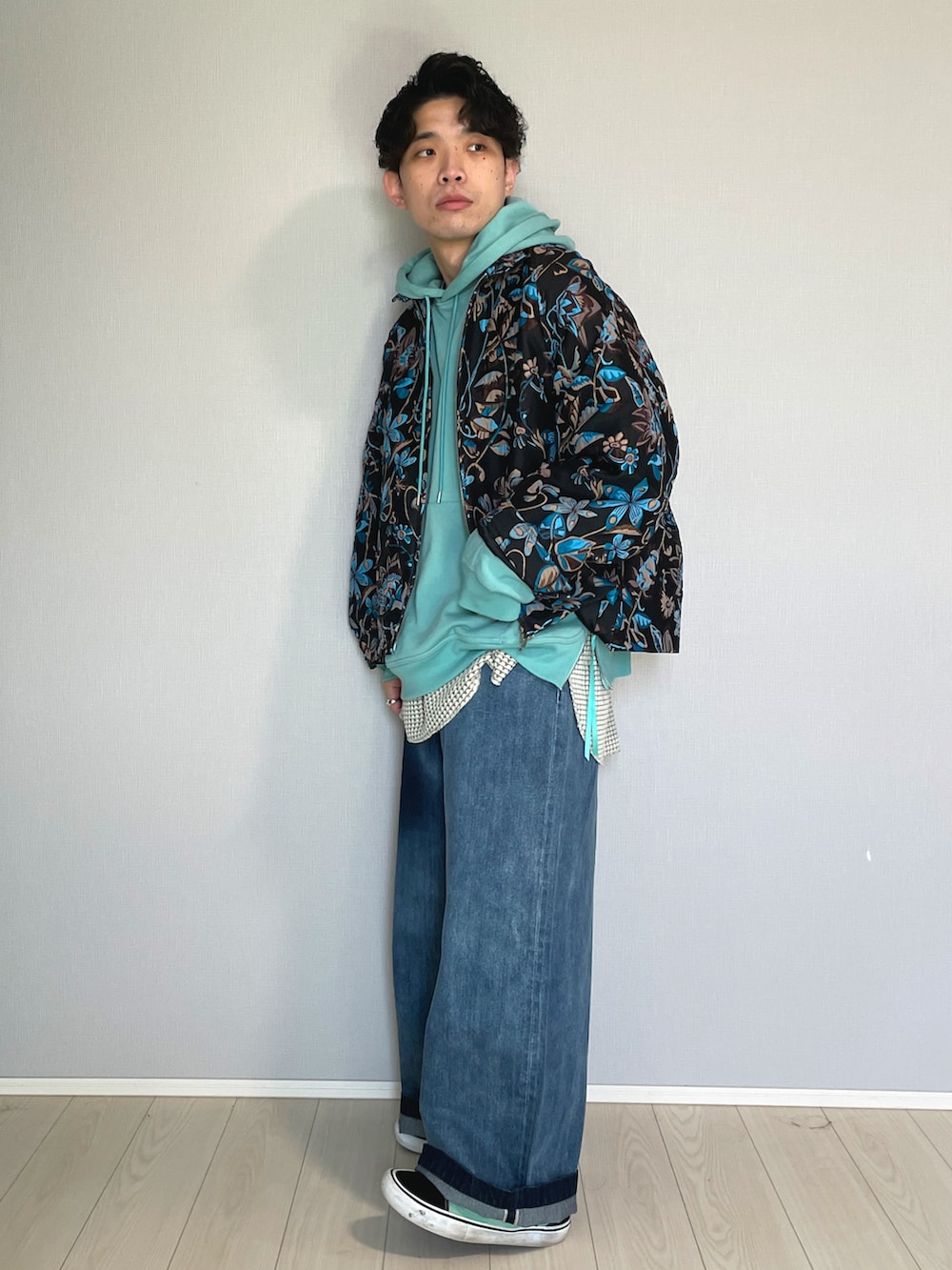 ブラック系のスニーカー、ブルー系のデニムパンツ、グリーン系のパーカーを着用したメンズの春コーディネートの2枚目の写真