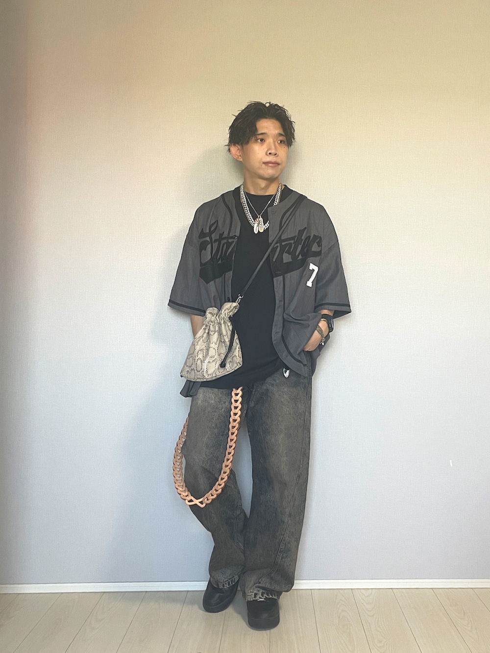 ブラック系のスニーカー、ブルー系のデニムパンツ、ベージュ系のショルダーバッグを着用したメンズの秋コーディネートの2枚目の写真