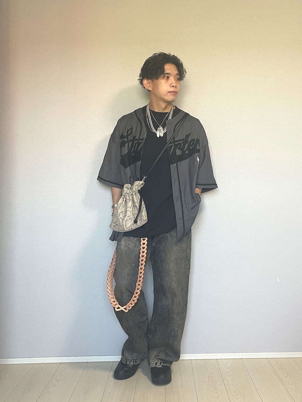 ブラック系のスニーカー、ブルー系のデニムパンツ、ベージュ系のショルダーバッグを着用したメンズの秋コーディネートの4枚目の写真