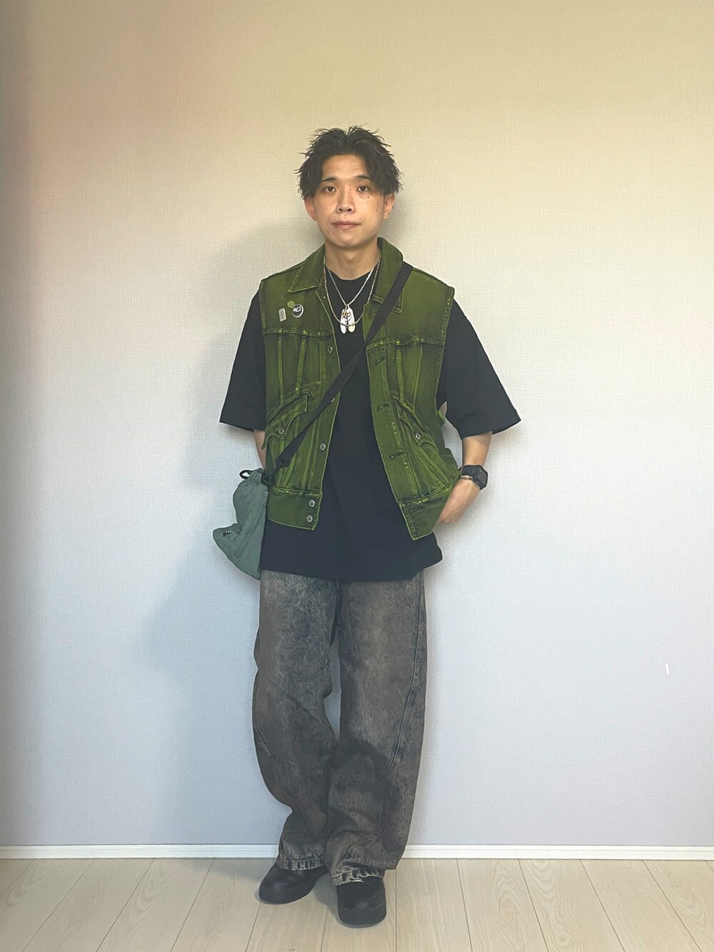 ブラック系のスニーカー、ブルー系のデニムパンツ、イエロー系のベストを着用したメンズの秋コーディネートの5枚目の写真