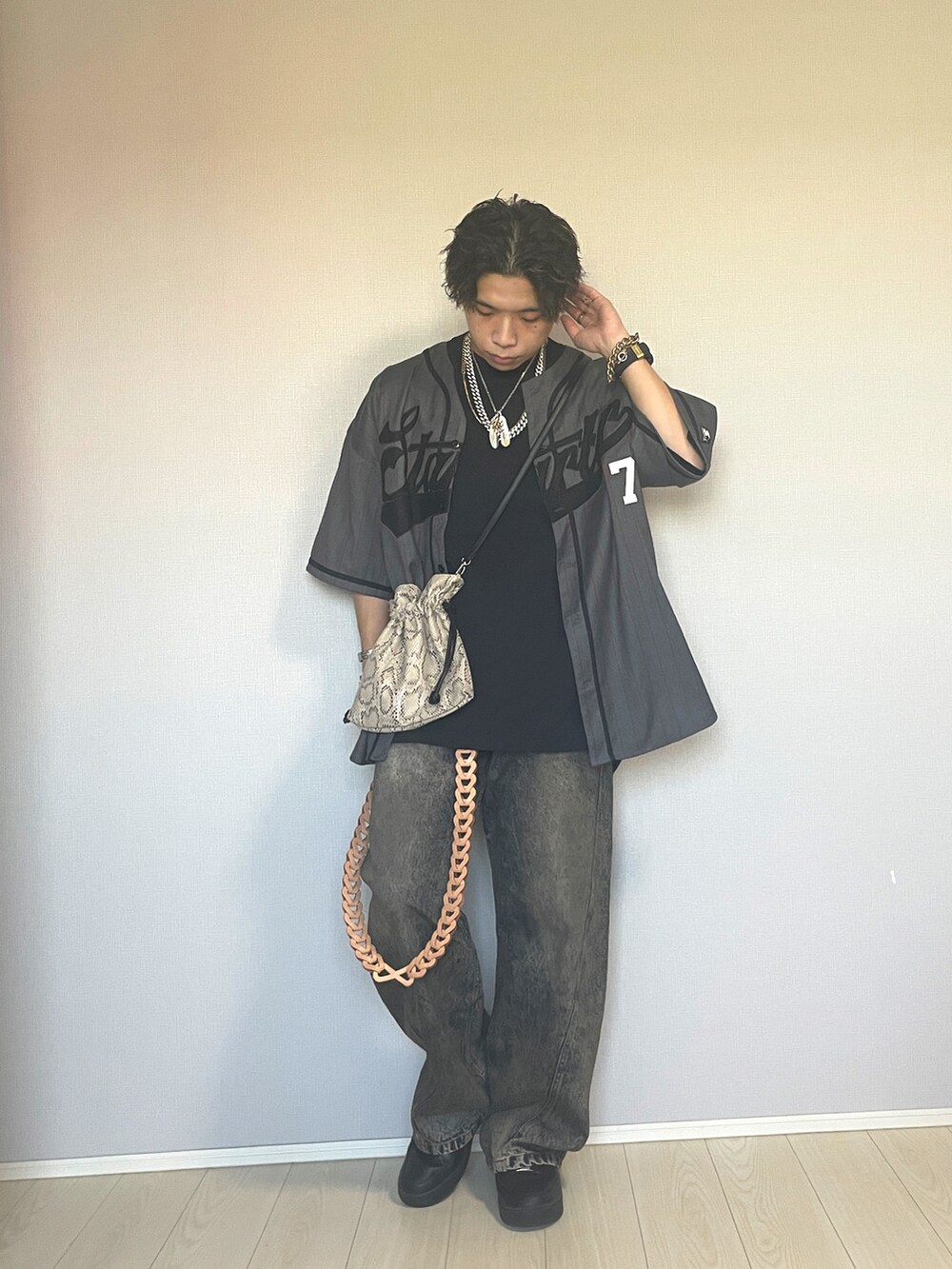 ブラック系のスニーカー、ブルー系のデニムパンツ、ベージュ系のショルダーバッグを着用したメンズの秋コーディネートの3枚目の写真