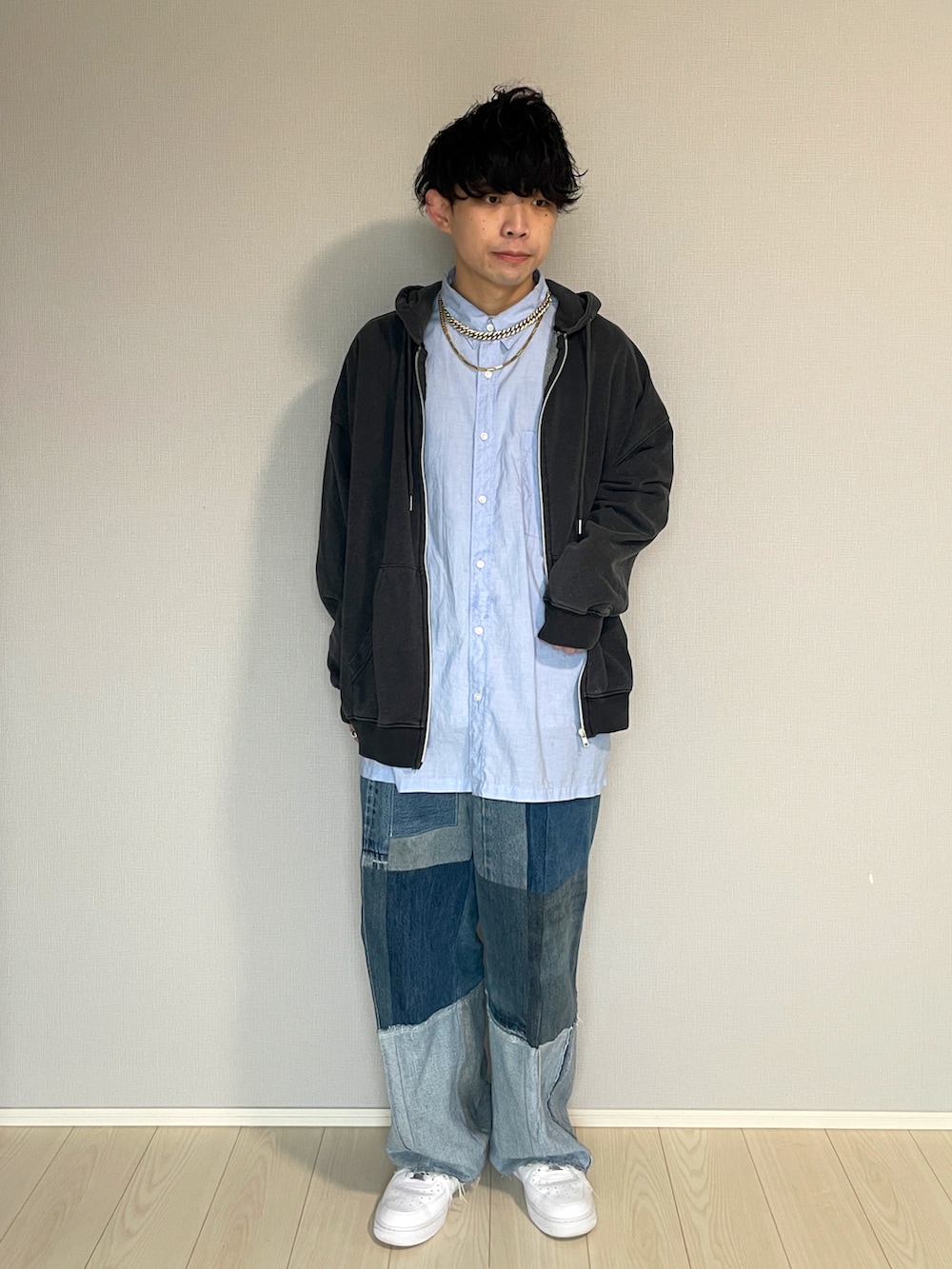 ブルー系のデニムパンツ、ホワイト系のスニーカー、ブラック系のパーカーを着用したメンズの春コーディネートの2枚目の写真