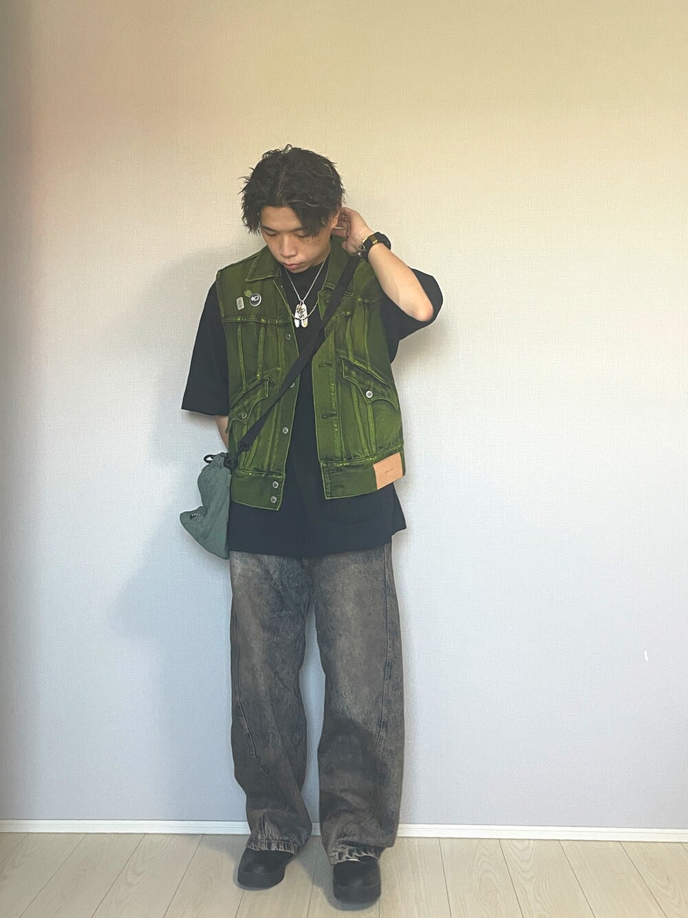 ブラック系のスニーカー、ブルー系のデニムパンツ、イエロー系のベストを着用したメンズの秋コーディネートの4枚目の写真