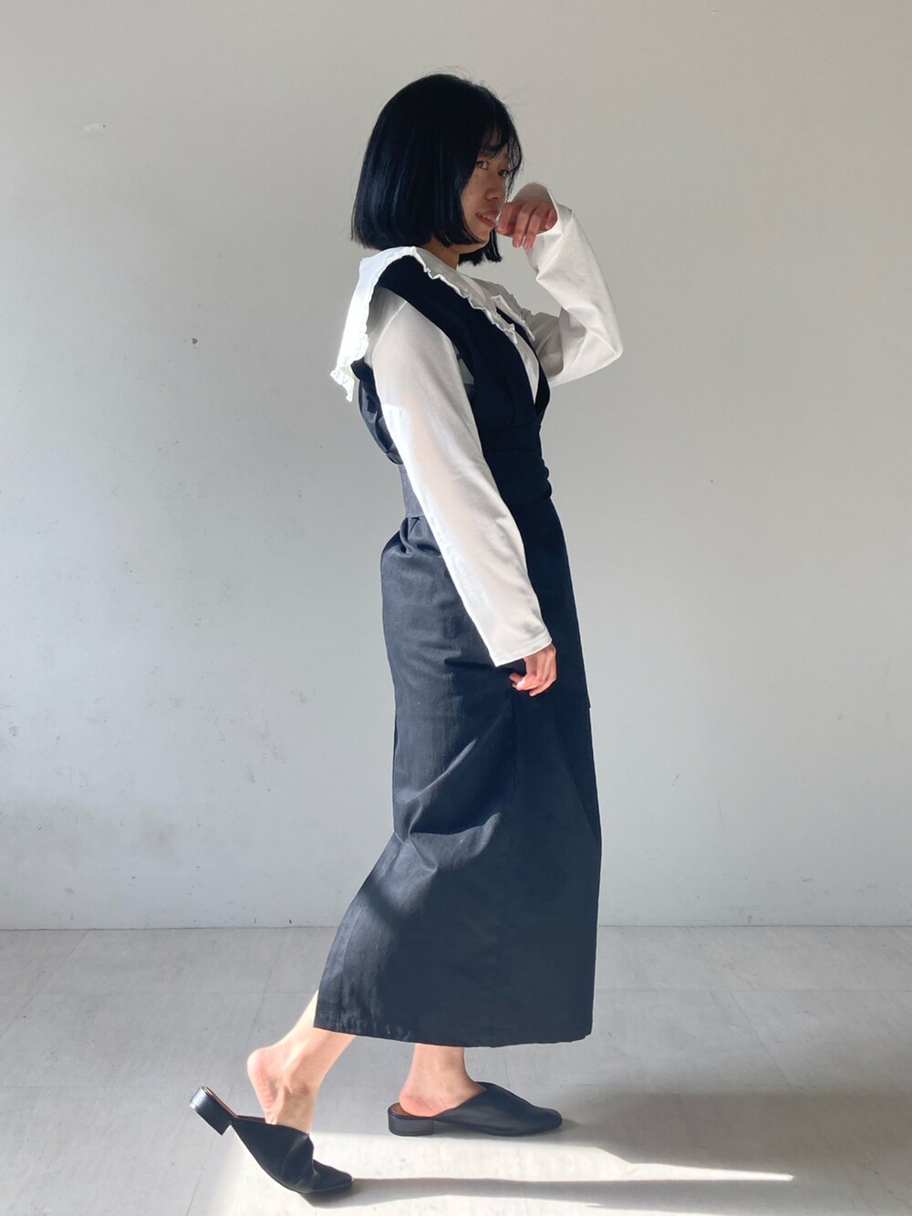 ホワイト系のTシャツ/カットソー、ブラック系のローファー、ブラック系のジャンパースカートを着用したレディースの冬コーディネートの3枚目の写真