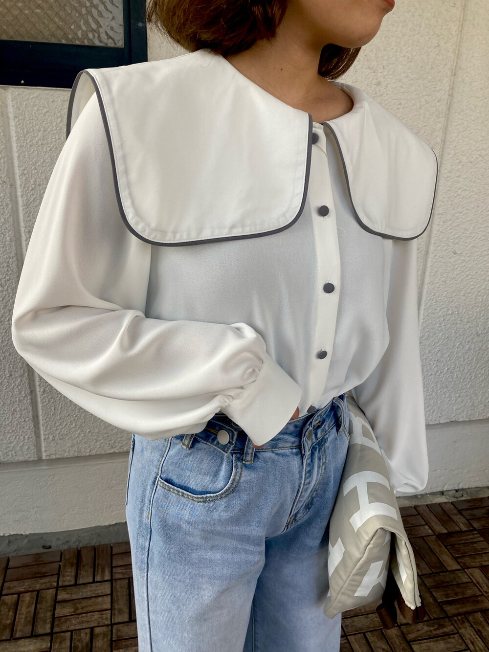 グレー系のトートバッグ、ホワイト系のシャツ/ブラウス、ブルー系のデニムパンツを着用したレディースの春コーディネートの3枚目の写真