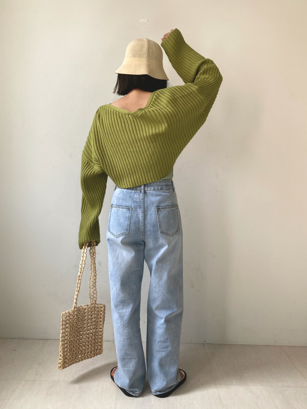 グリーン系のカーディガン/ボレロ、ブルー系のデニムパンツ、ベージュ系のバッグを着用したレディースの春コーディネートの2枚目の写真