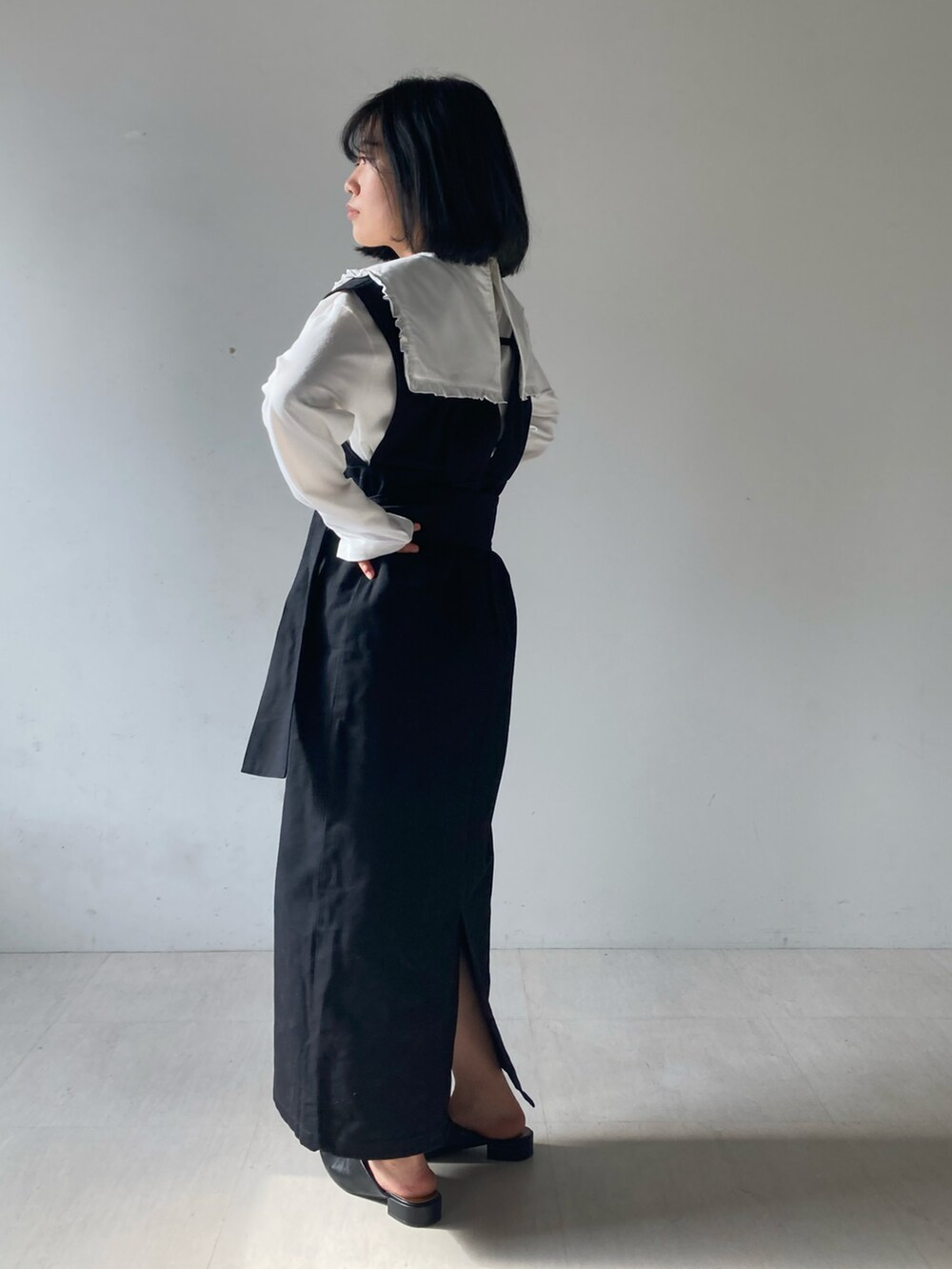 ホワイト系のTシャツ/カットソー、ブラック系のローファー、ブラック系のジャンパースカートを着用したレディースの冬コーディネートの2枚目の写真