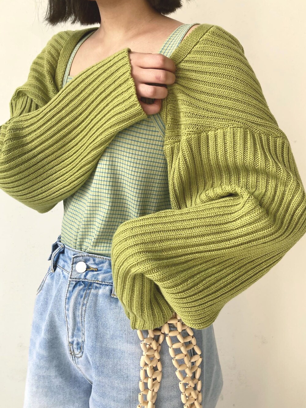 グリーン系のカーディガン/ボレロ、ブルー系のデニムパンツ、ベージュ系のバッグを着用したレディースの春コーディネートの3枚目の写真