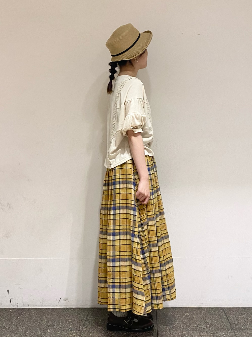 イエロー系のスカート、ホワイト系のTシャツ/カットソー、ベージュ系のハットを着用したレディースの夏コーディネートの4枚目の写真