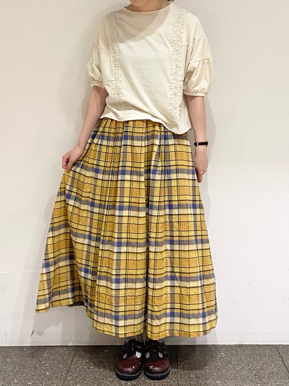 イエロー系のスカート、ホワイト系のTシャツ/カットソー、ベージュ系のハットを着用したレディースの夏コーディネートの5枚目の写真