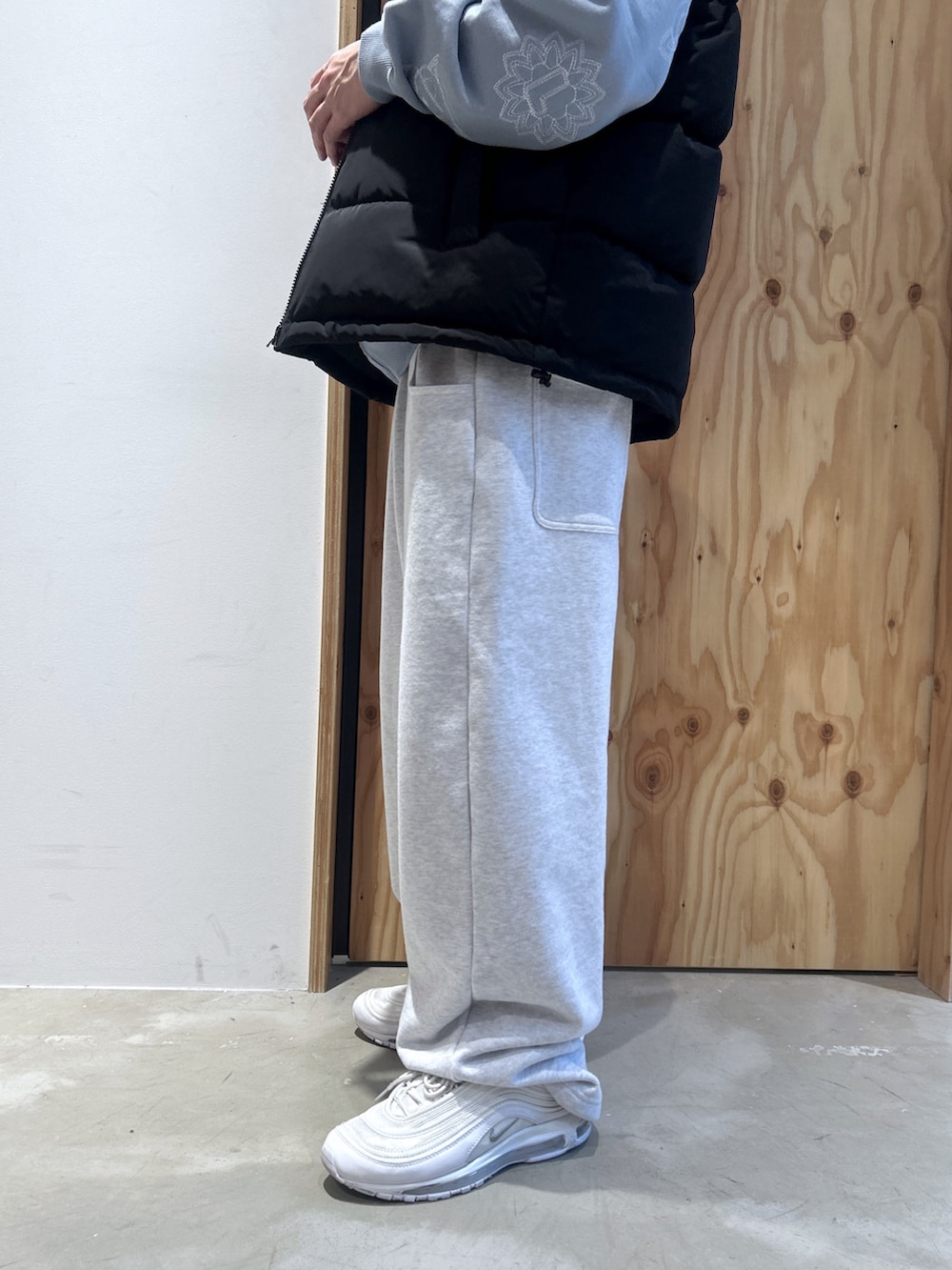 ブラック系のダウンベスト、ブルー系のパーカー、グレー系のスウェットパンツを着用したメンズの秋コーディネートの4枚目の写真