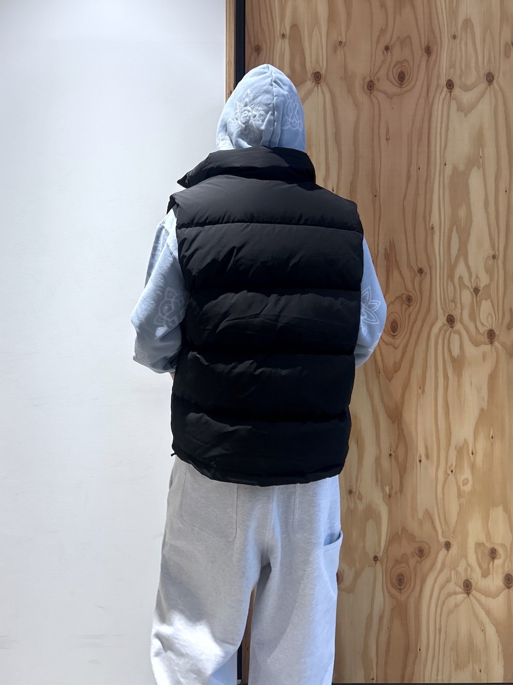 ブラック系のダウンベスト、ブルー系のパーカー、グレー系のスウェットパンツを着用したメンズの秋コーディネートの3枚目の写真