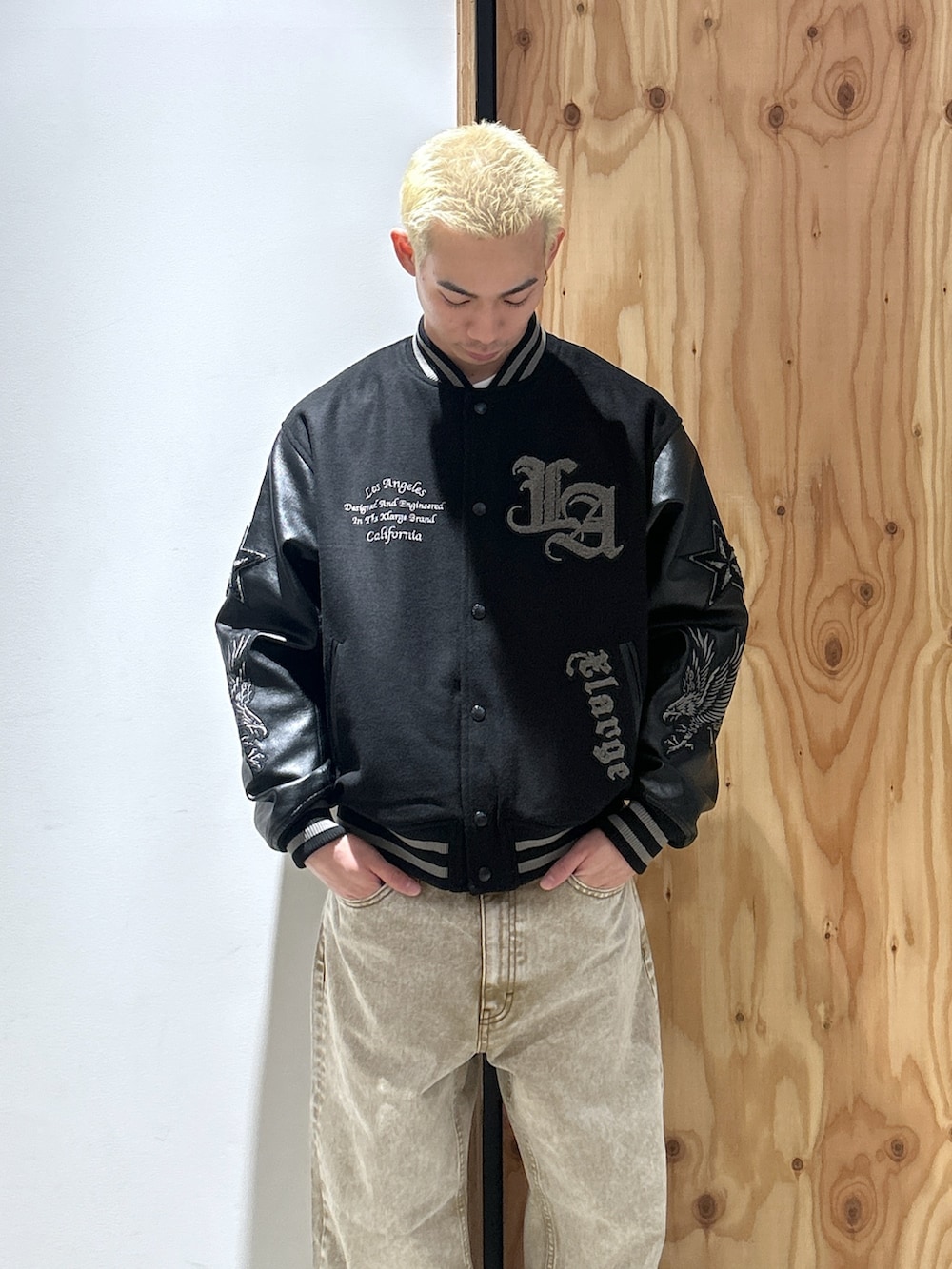 ブラック系のスタジャン、ベージュ系のデニムパンツを着用したメンズの秋コーディネートの2枚目の写真