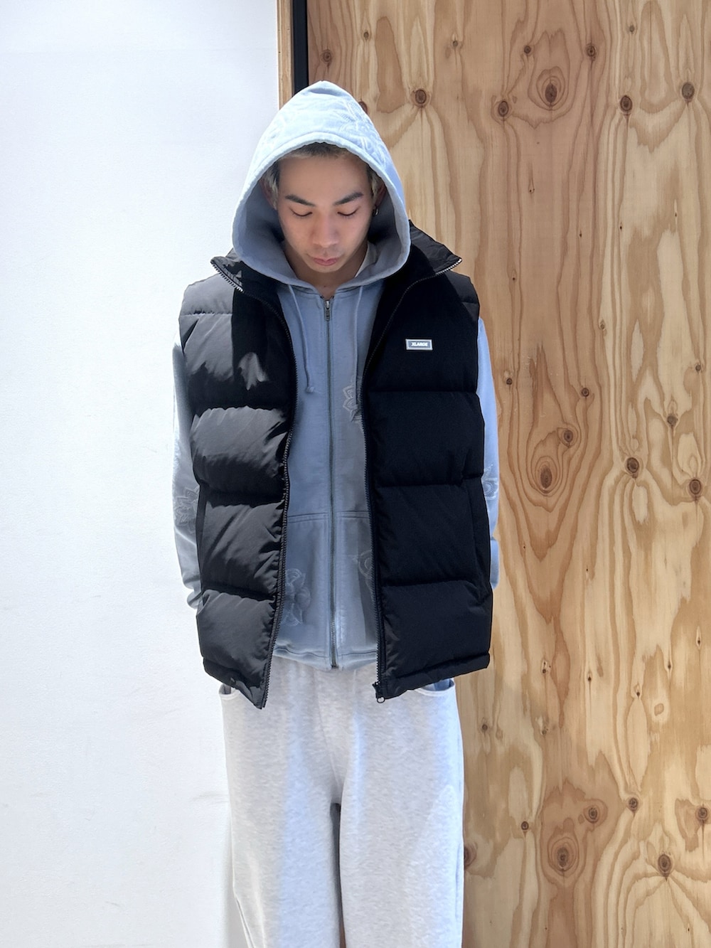 ブラック系のダウンベスト、ブルー系のパーカー、グレー系のスウェットパンツを着用したメンズの秋コーディネートの2枚目の写真