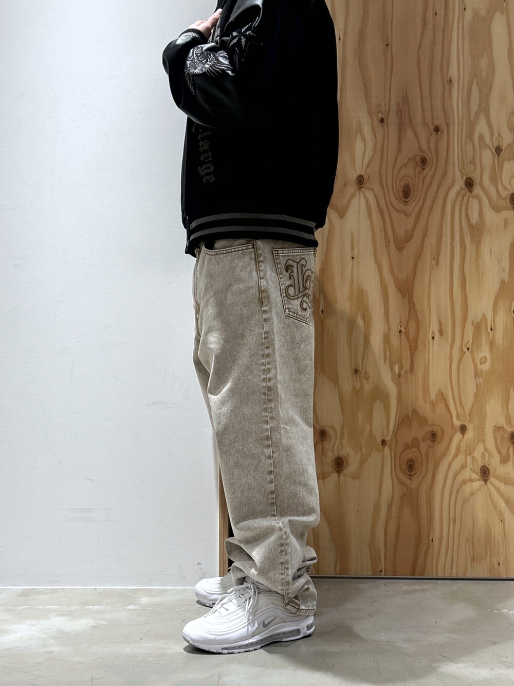 ブラック系のスタジャン、ベージュ系のデニムパンツを着用したメンズの秋コーディネートの4枚目の写真