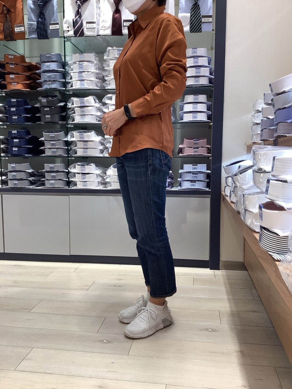 ブラウン系のニット/セーター、オレンジ系のビジネスシャツを着用したレディースの秋コーディネートの2枚目の写真