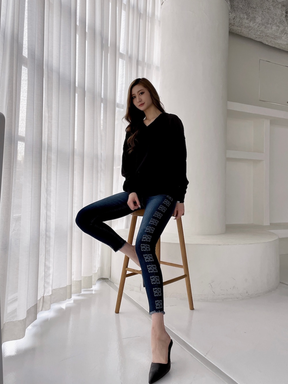 ブラック系のスウェット、ブルー系のデニムパンツ、ブラック系のパンプスを着用したレディースの冬コーディネートの4枚目の写真