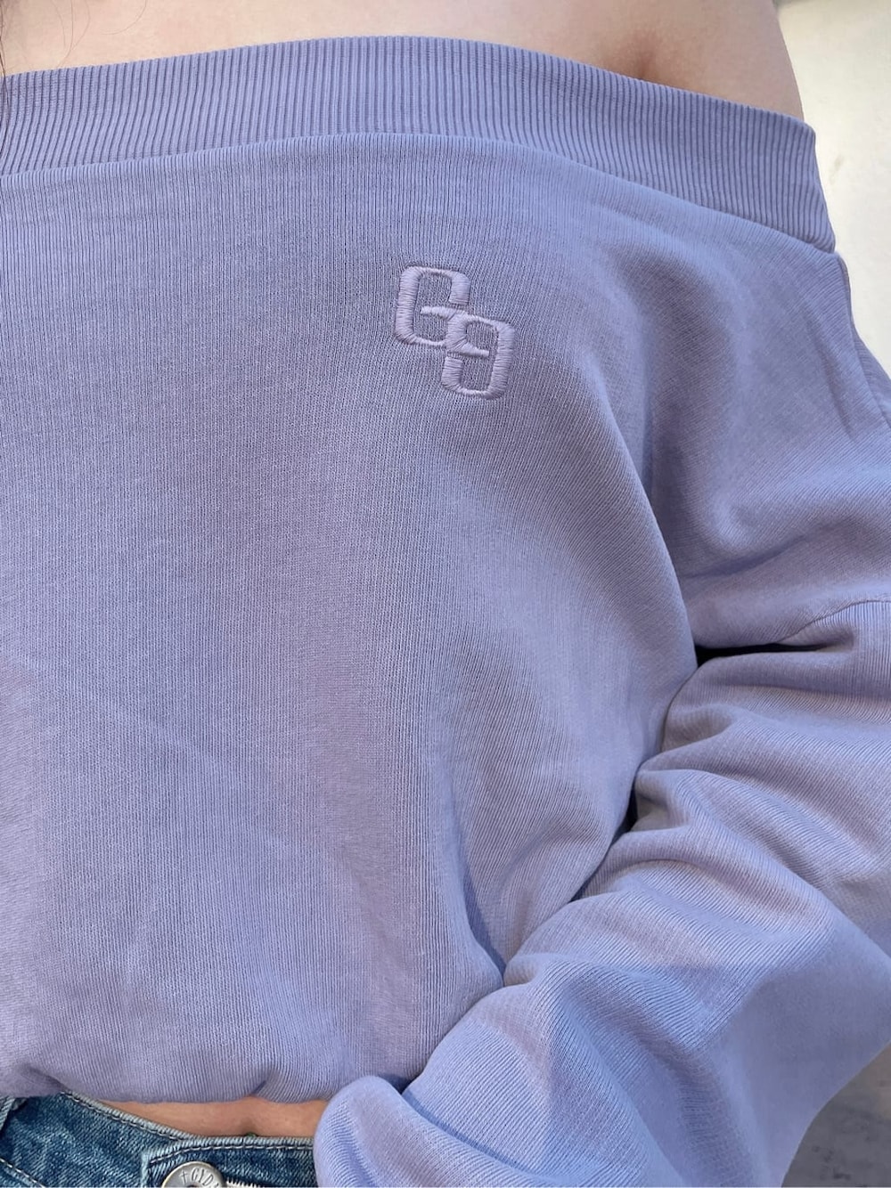 ホワイト系のパンプス、パープル系のスウェット、ブルー系のデニムパンツを着用したレディースの冬コーディネートの4枚目の写真