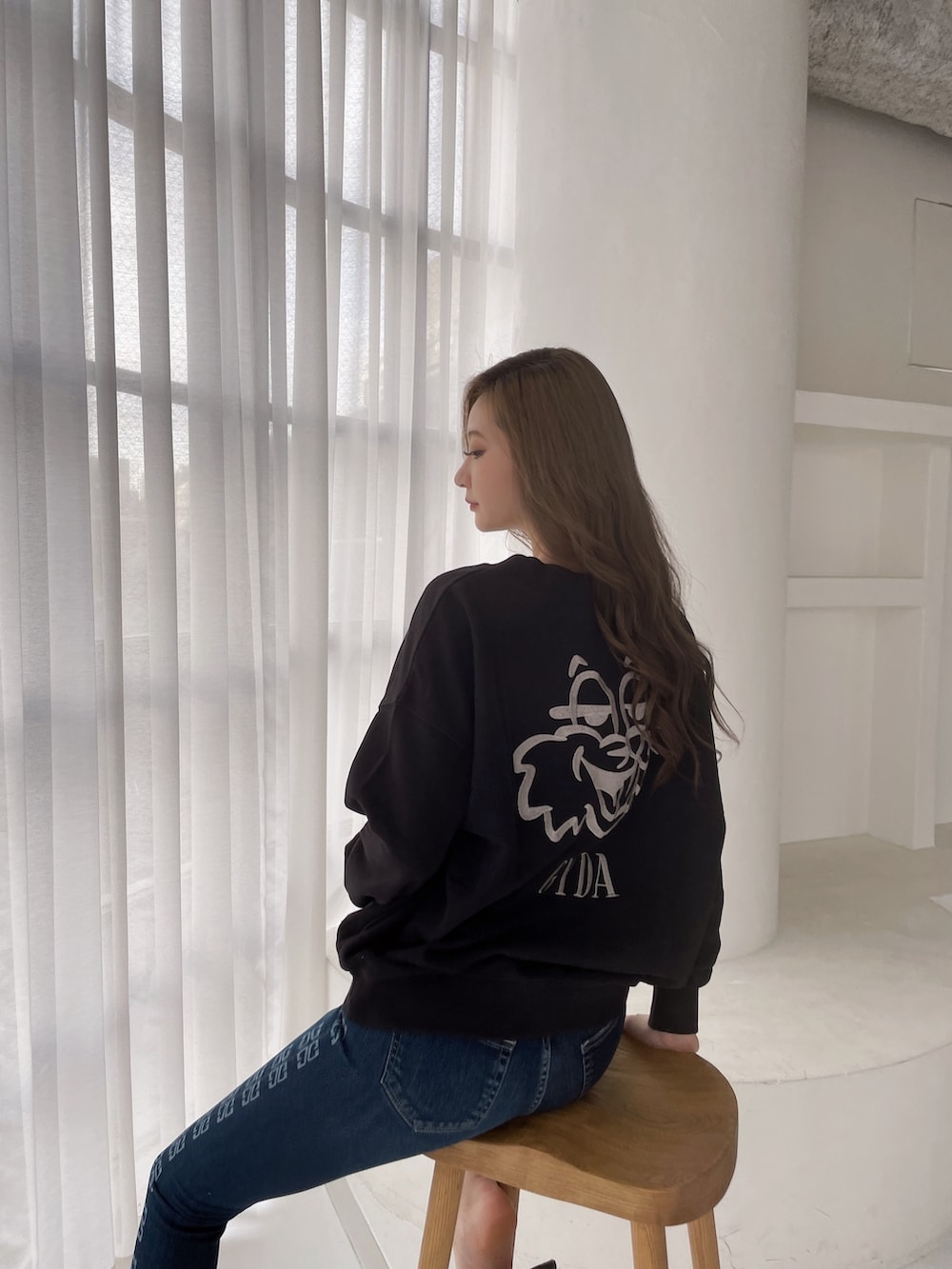 ブラック系のスウェット、ブルー系のデニムパンツ、ブラック系のパンプスを着用したレディースの冬コーディネートの3枚目の写真