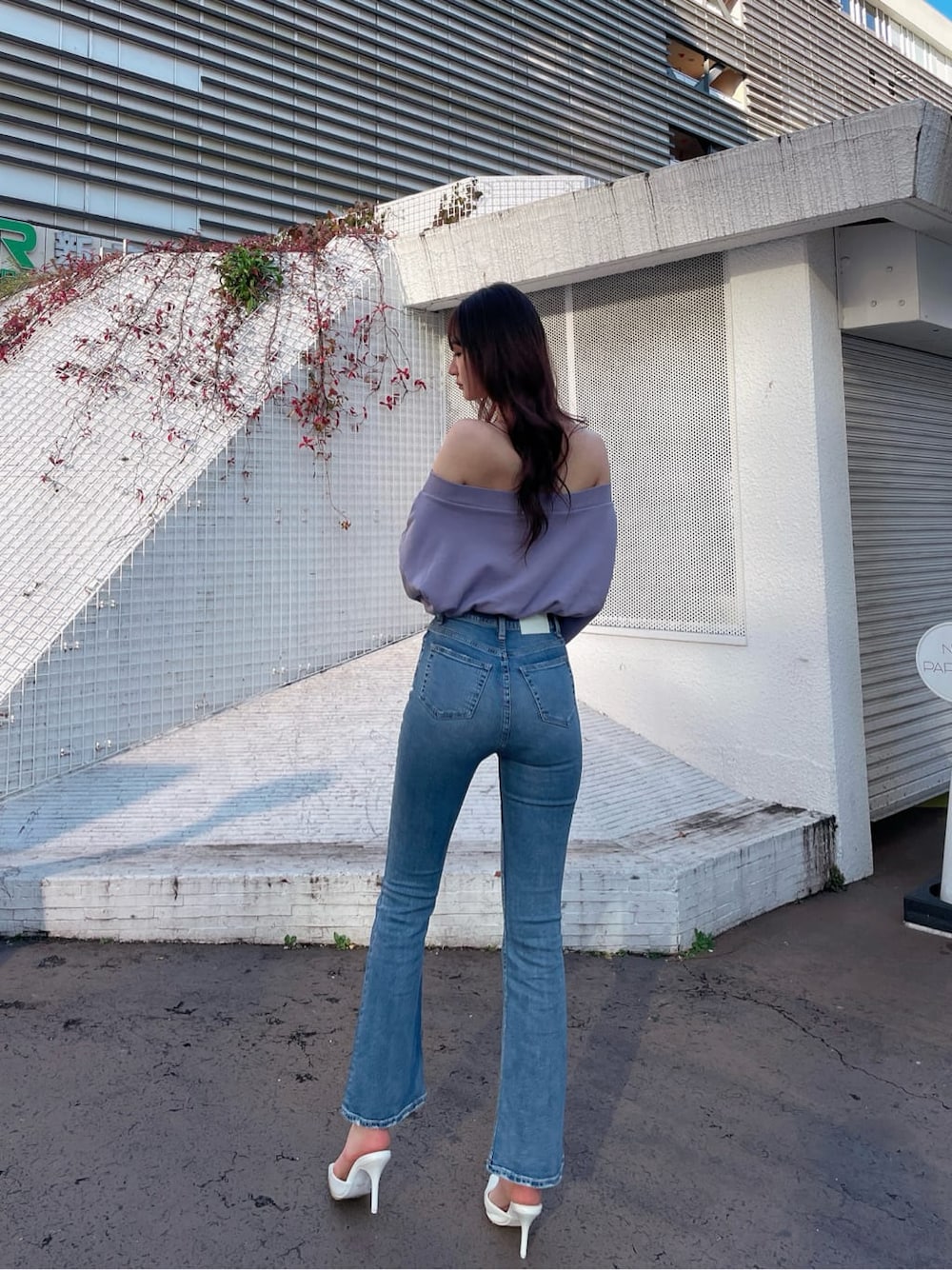 ホワイト系のパンプス、パープル系のスウェット、ブルー系のデニムパンツを着用したレディースの冬コーディネートの2枚目の写真