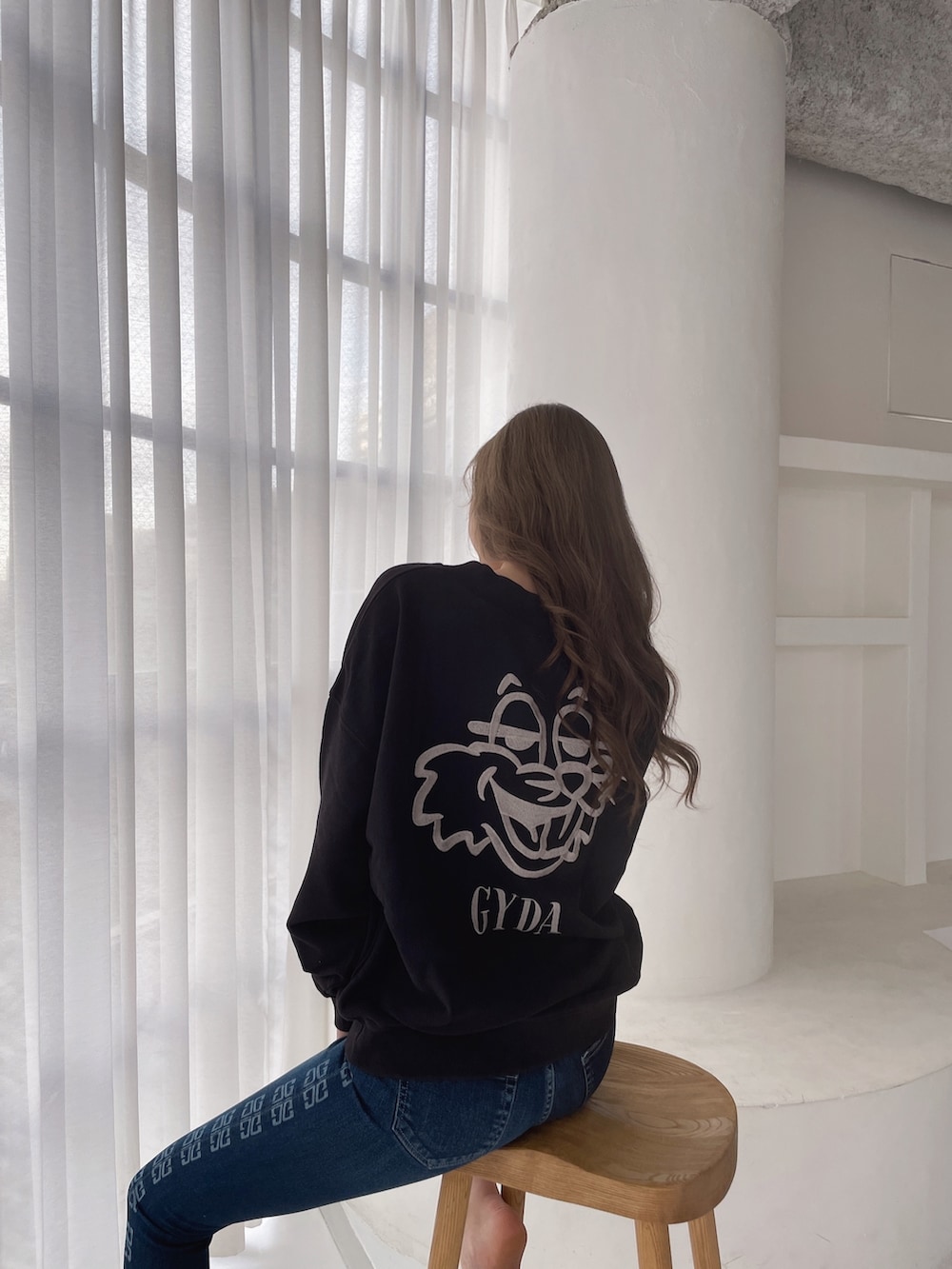 ブラック系のスウェット、ブルー系のデニムパンツ、ブラック系のパンプスを着用したレディースの冬コーディネートの2枚目の写真