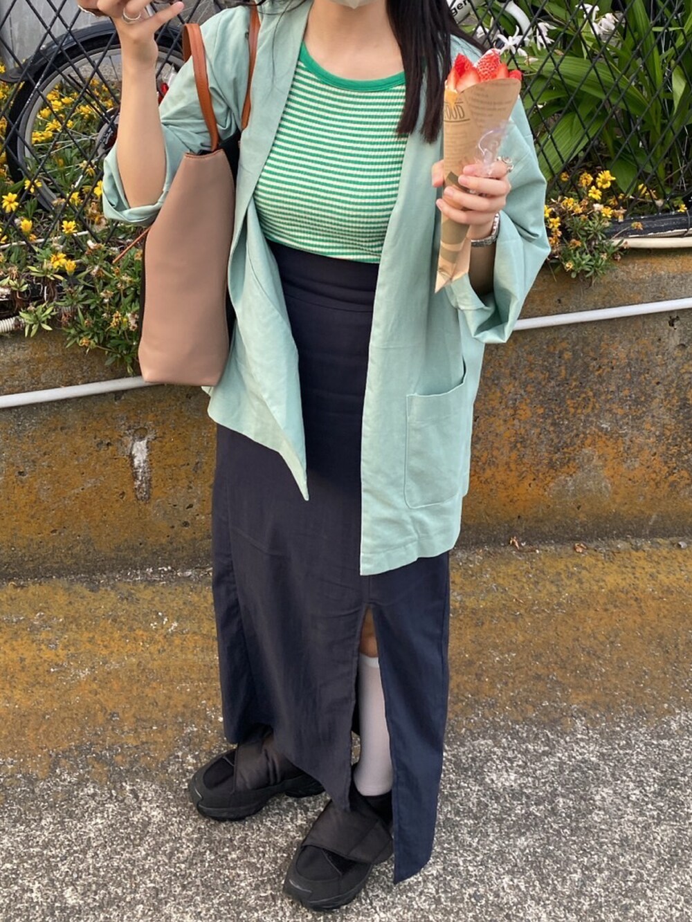 ブルー系のノーカラージャケット、ブラック系のトートバッグ、グリーン系のTシャツ/カットソーを着用したレディースの春コーディネートの2枚目の写真