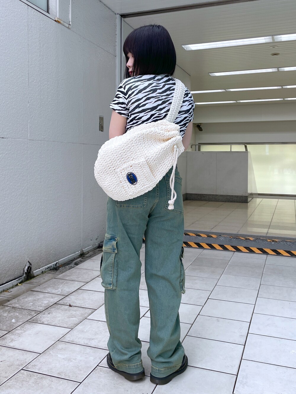 ホワイト系のショルダーバッグ、ホワイト系のTシャツ/カットソー、ブルー系のデニムパンツを着用したレディースの夏コーディネートの2枚目の写真