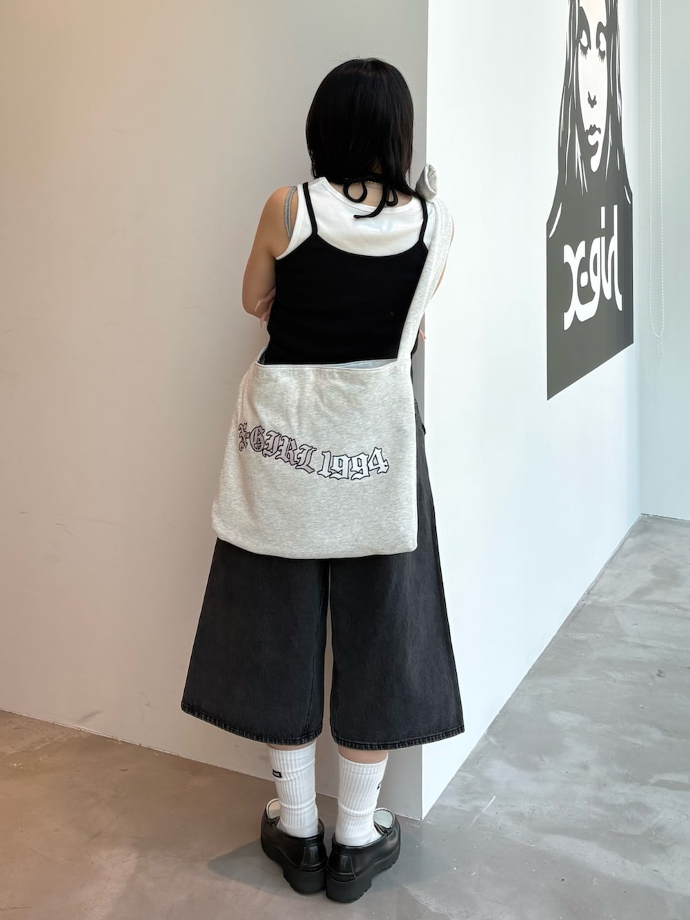 ブルー系のデニムパンツ、ベージュ系のキャミソール、グレー系のショルダーバッグを着用したレディースの春コーディネートの3枚目の写真