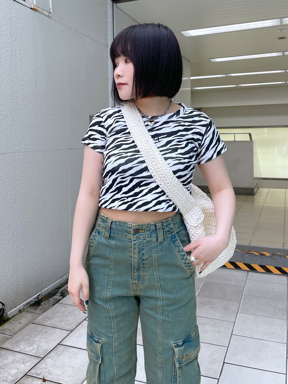 ホワイト系のショルダーバッグ、ホワイト系のTシャツ/カットソー、ブルー系のデニムパンツを着用したレディースの夏コーディネートの3枚目の写真