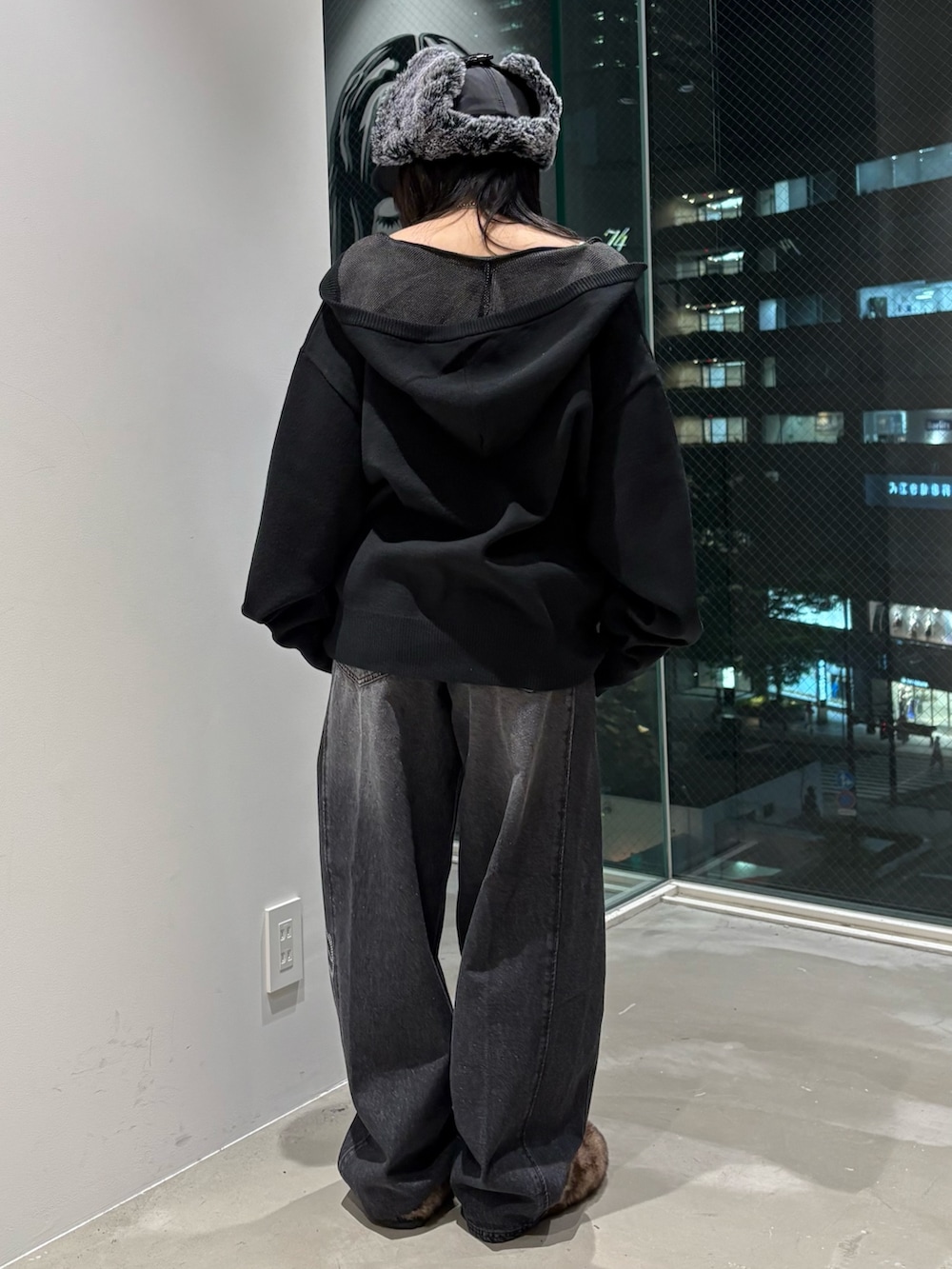 ブラック系のデニムパンツ、ブラック系のニット/セーター、ブラック系のキャップを着用したレディースの秋コーディネートの3枚目の写真