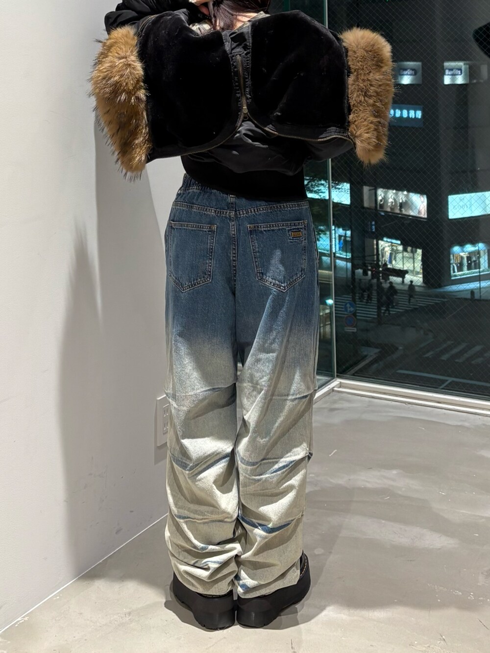 ブラック系のナイロンジャケット、ブルー系のデニムパンツ、グリーン系のTシャツ/カットソーを着用したレディースの秋コーディネートの2枚目の写真