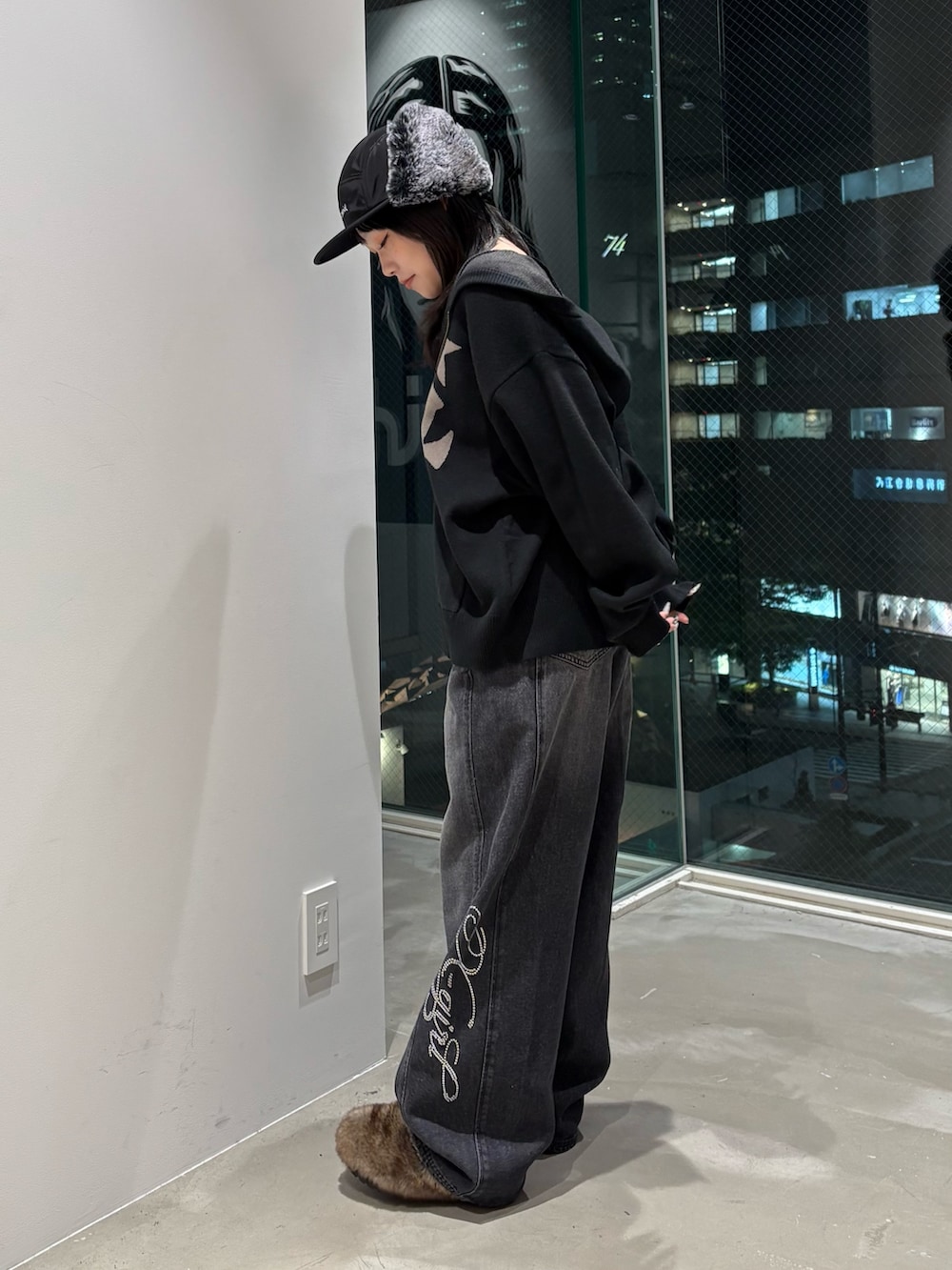 ブラック系のデニムパンツ、ブラック系のニット/セーター、ブラック系のキャップを着用したレディースの秋コーディネートの2枚目の写真