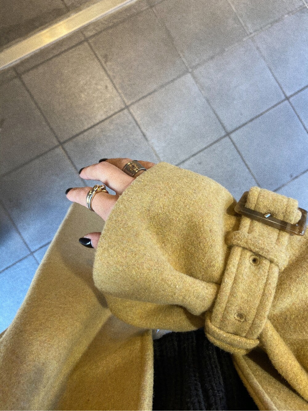 ブラック系のデニムパンツ、ブラック系のニット/セーター、イエロー系のステンカラーコートを着用したレディースの冬コーディネートの2枚目の写真