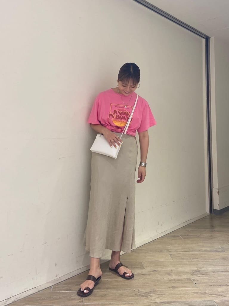 ピンク系のTシャツ/カットソー、ベージュ系のスカート、ホワイト系のショルダーバッグを着用したレディースの夏コーディネートの2枚目の写真