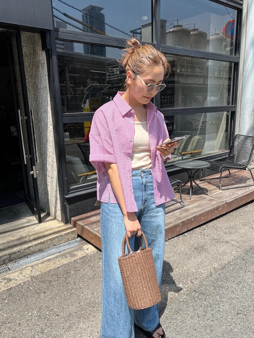 パープル系のシャツ/ブラウス、ブルー系のデニムパンツ、ブラウン系のかごバッグを着用したレディースの春コーディネートの4枚目の写真