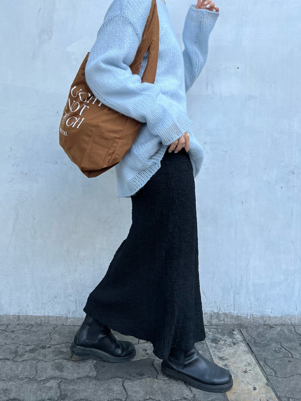 ブルー系のニット/セーター、ブラック系のスカート、ブラウン系のエコバッグ/サブバッグを着用したレディースの冬コーディネートの3枚目の写真