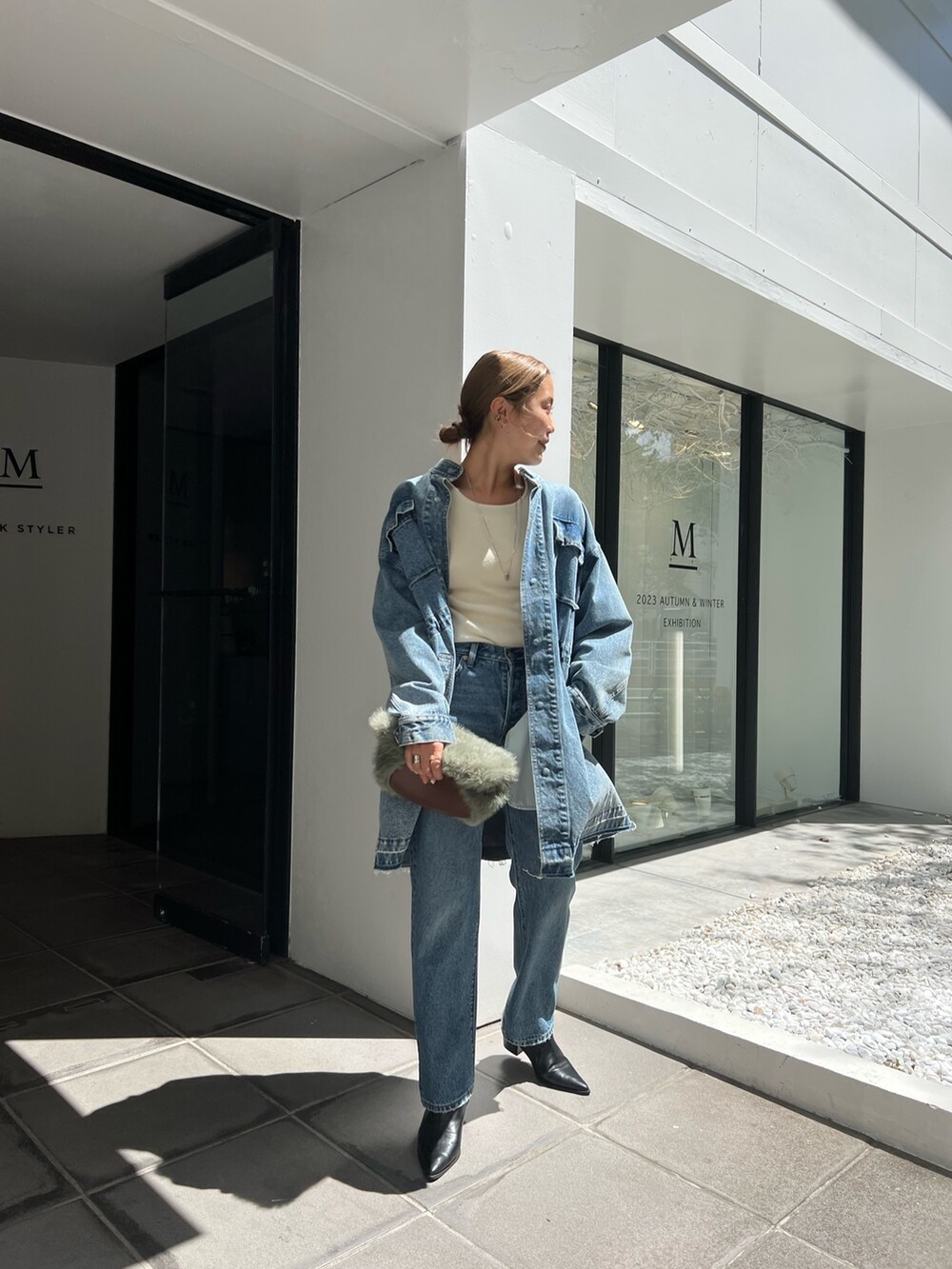 ブルー系のデニムジャケット、ブルー系のデニムパンツ、グリーン系のハンドバッグを着用したレディースの夏コーディネートの3枚目の写真