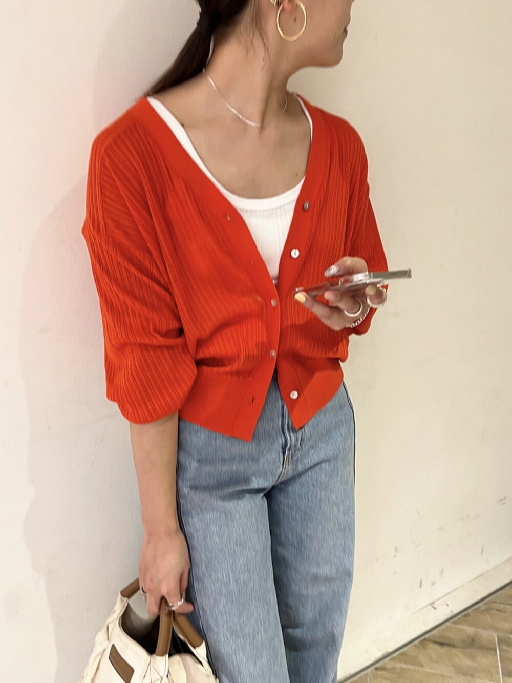 オレンジ系のカーディガン/ボレロ、ブルー系のデニムパンツ、ゴールド系のパンプスを着用したレディースの春コーディネートの4枚目の写真