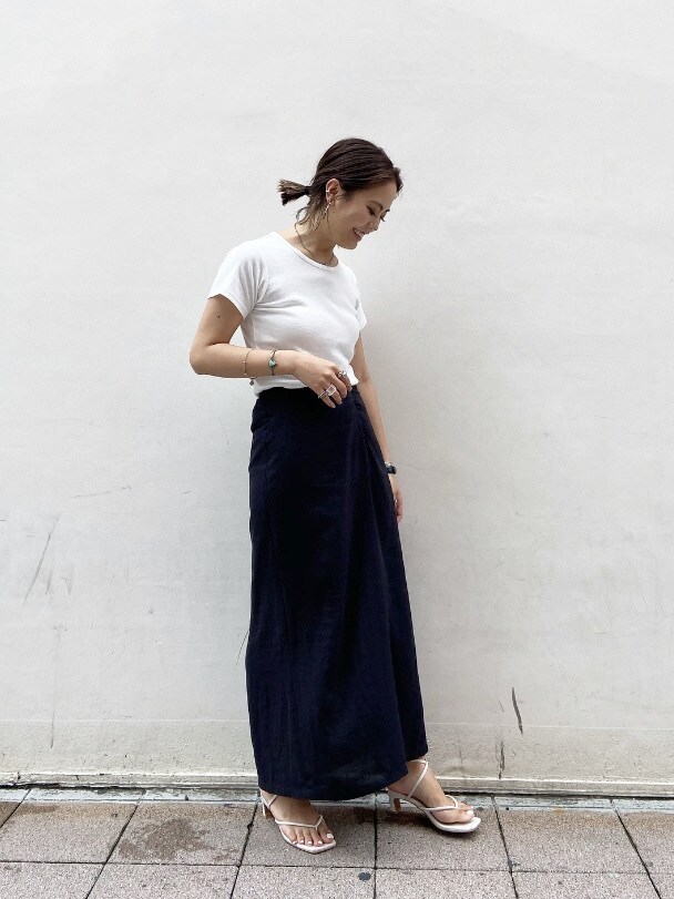 ブラック系のスカート、ホワイト系のサンダル、ホワイト系のTシャツ/カットソーを着用したレディースの夏コーディネートの3枚目の写真