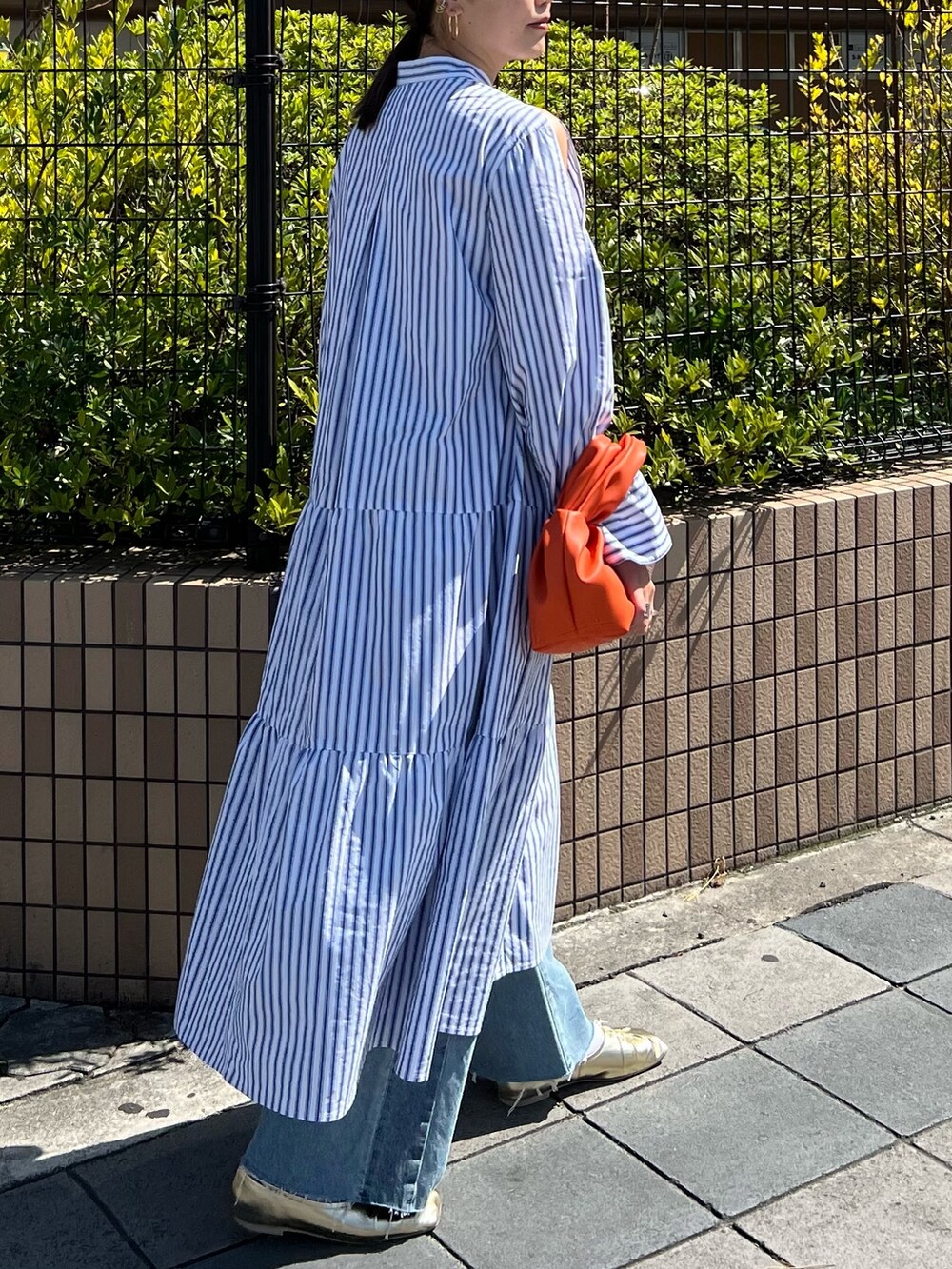 その他のワンピース、オレンジ系のハンドバッグ、ゴールド系のパンプスを着用したレディースの春コーディネートの2枚目の写真