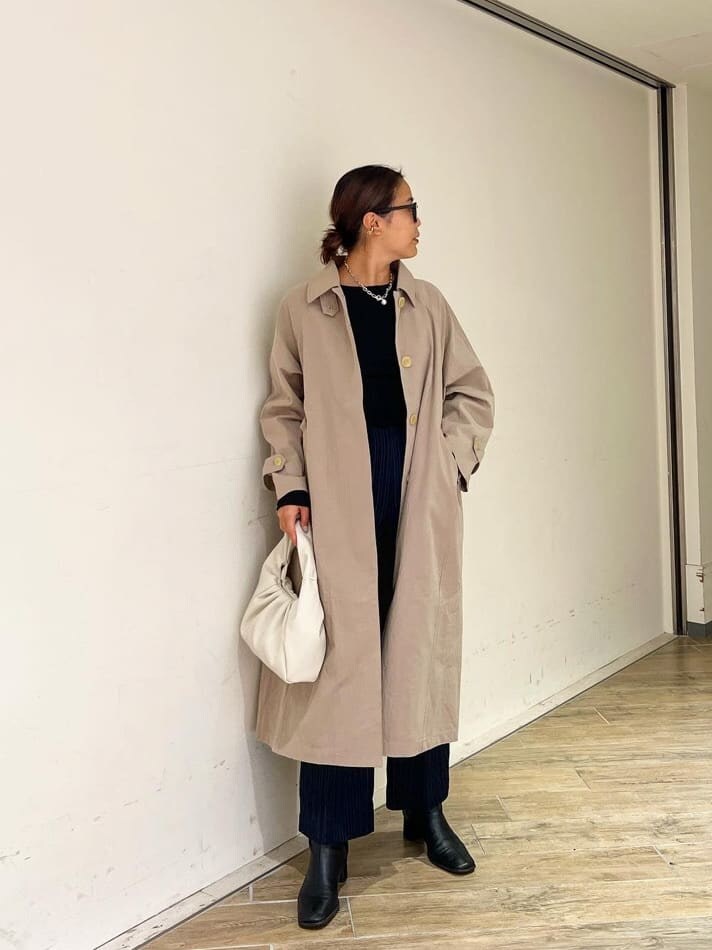 ベージュ系のステンカラーコート、ブラック系のブーツ、ブラック系のTシャツ/カットソーを着用したレディースの秋コーディネートの4枚目の写真