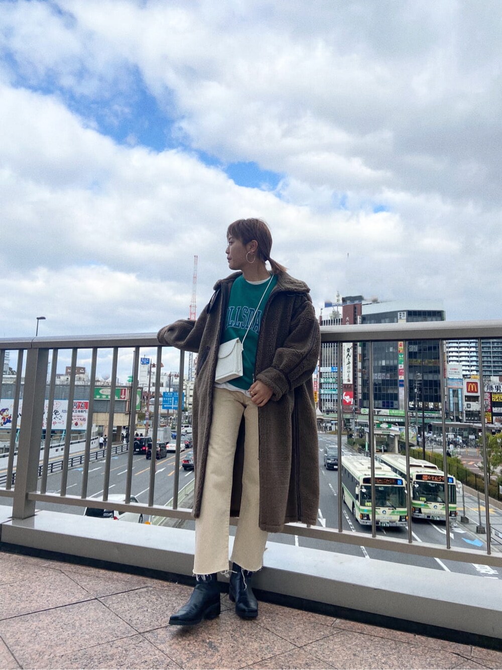 グリーン系のスウェット、ホワイト系のデニムパンツ、ホワイト系のショルダーバッグを着用したレディースの冬コーディネートの4枚目の写真