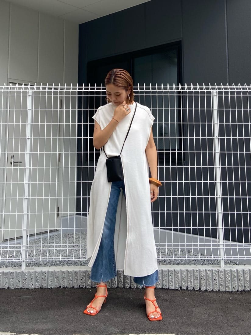 オレンジ系のサンダル、ブルー系のデニムパンツ、ホワイト系のワンピースを着用したレディースの夏コーディネートの3枚目の写真