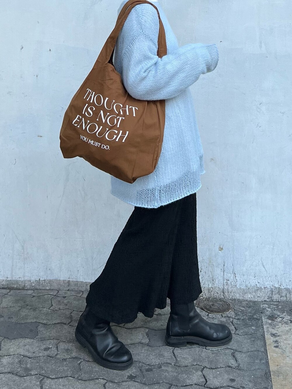 ブルー系のニット/セーター、ブラック系のスカート、ブラウン系のエコバッグ/サブバッグを着用したレディースの冬コーディネートの2枚目の写真