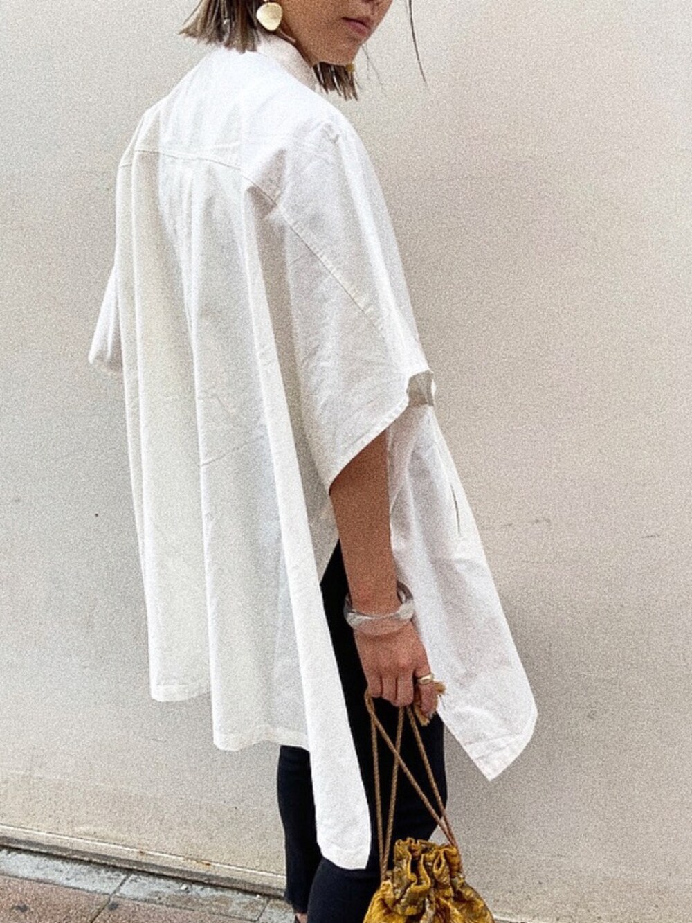 イエロー系のハンドバッグ、ホワイト系のシャツ/ブラウス、ブラック系のデニムパンツを着用したレディースの夏コーディネートの3枚目の写真