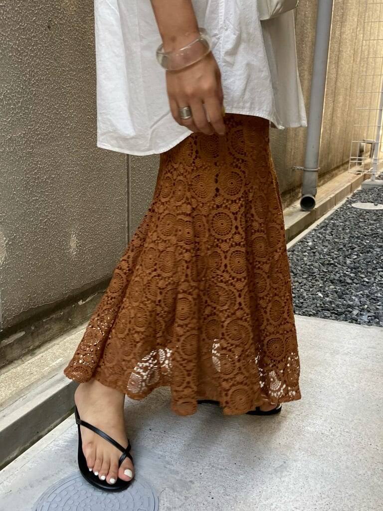 ホワイト系のシャツ/ブラウス、ブラウン系のスカート、シルバー系のブレスレットを着用したレディースの夏コーディネートの2枚目の写真