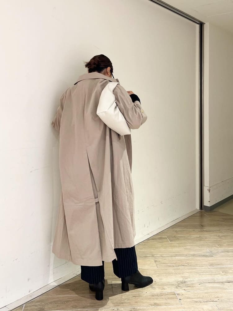 ベージュ系のステンカラーコート、ブラック系のブーツ、ブラック系のTシャツ/カットソーを着用したレディースの秋コーディネートの3枚目の写真