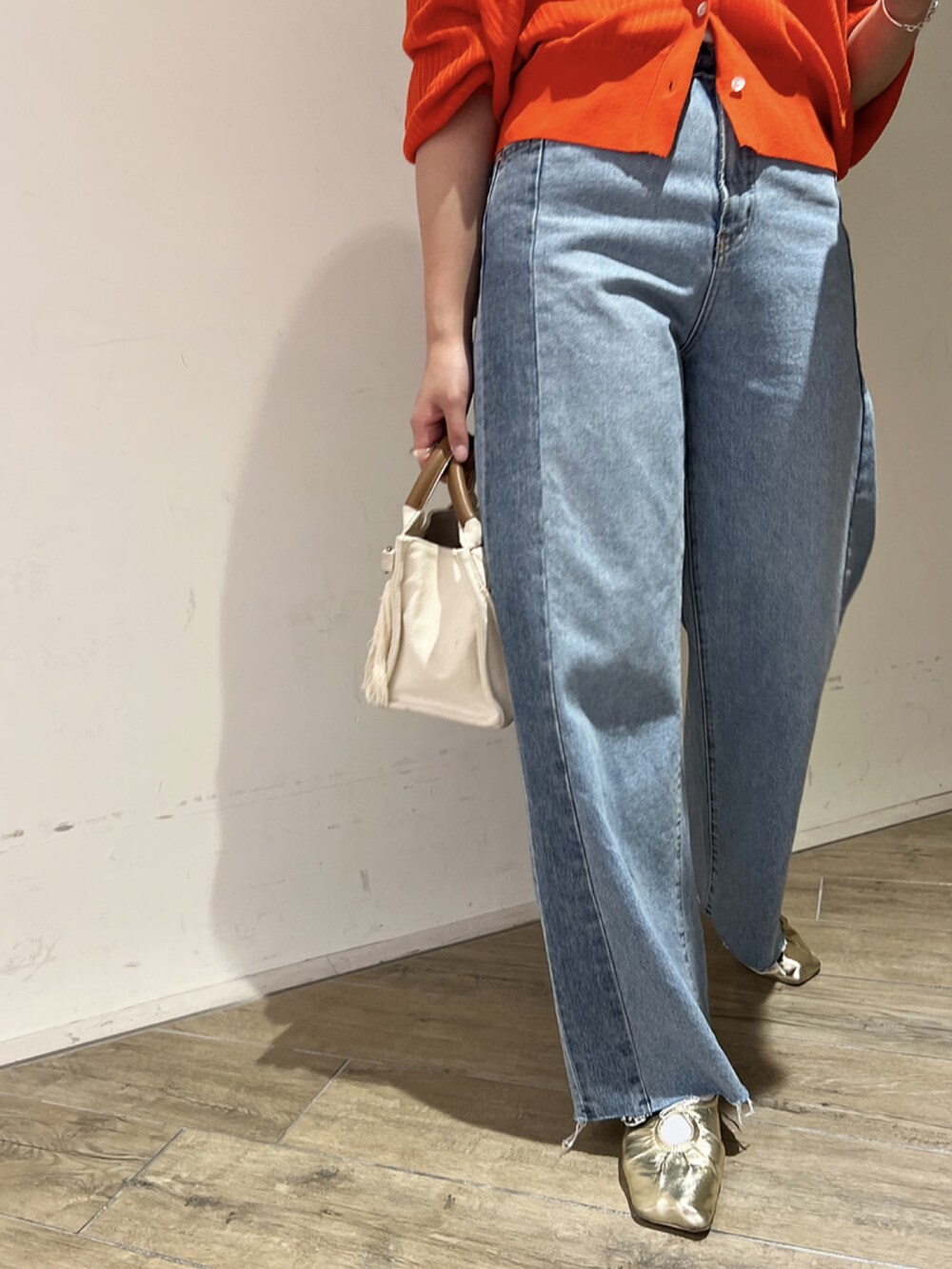 オレンジ系のカーディガン/ボレロ、ブルー系のデニムパンツ、ゴールド系のパンプスを着用したレディースの春コーディネートの3枚目の写真
